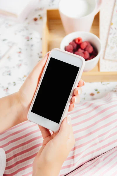 Genç kadın yatakta üstten görünüm elinde, eve telefon tutarak pijama