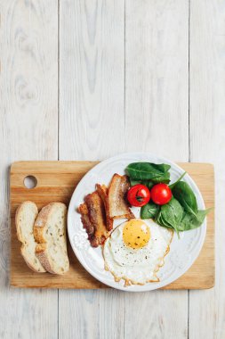 Lezzetli pastırma üst görünümü, bir yumurta ve ahşap masada ekmek iki adet.
