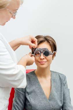 Açık gri arka planda optik deneme çerçevesinde gülümseyen kadın