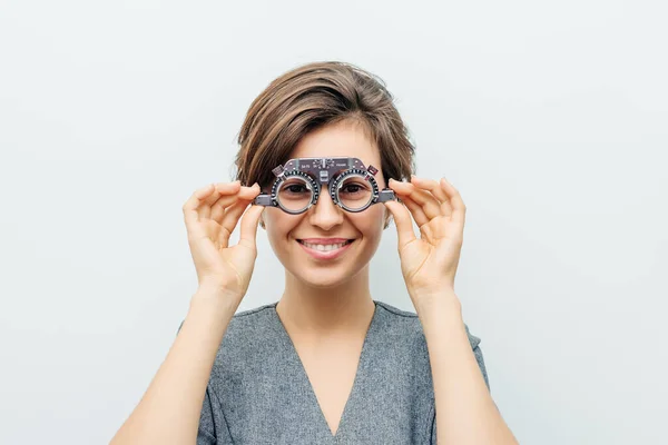 Mujer sonriente en marco de prueba óptica sobre fondo gris claro —  Fotos de Stock