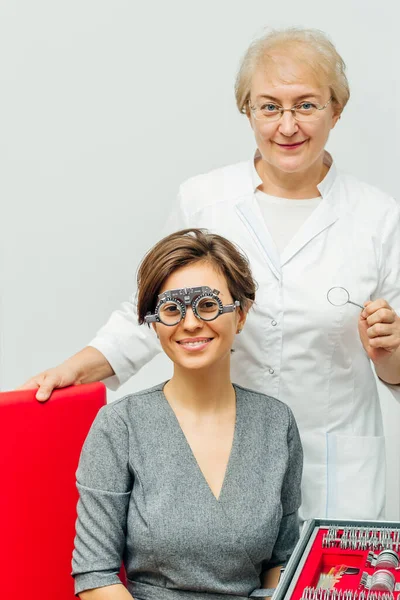 Lächelnder Augenarzt und Patient im optischen Versuchsrahmen auf hellgrauem Hintergrund — Stockfoto