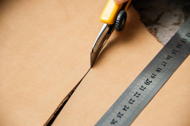 Masada deri ürünler üretirken kesme aracı ve metal cetvel üst görünümü