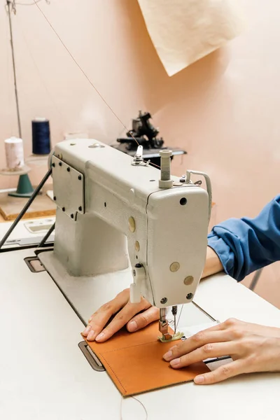 Oldalnézetben professzionális varrógép a műhelyben, női kéz tart egy darab sárga bőr — Stock Fotó