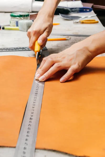 Pessoas mãos usando ferramenta de corte e régua de metal ao produzir artigos de couro — Fotografia de Stock