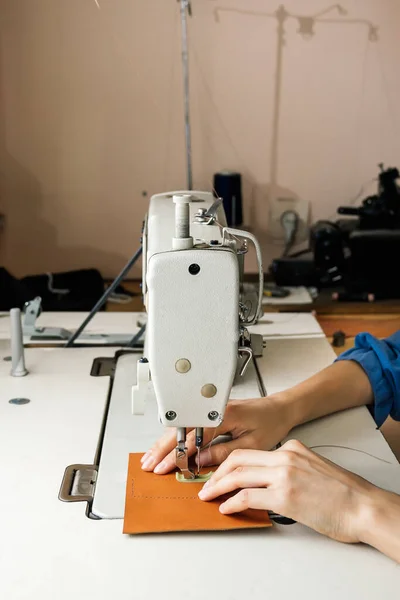 Vista lateral da máquina de costura profissional na oficina, as mãos das mulheres seguram um pedaço de couro amarelo — Fotografia de Stock