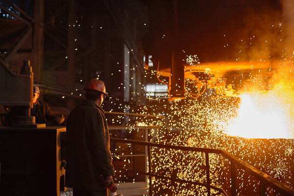 Steelmaker at ingot casting. Electric arc furnace shop EAF. Metallurgical production.