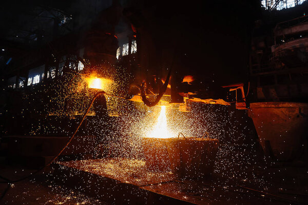 A stream of hot metal pours into the ladle. Electric arc furnace shop EAF. Metallurgy.