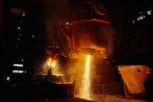 A stream of hot metal pours into the ladle. Electric arc furnace shop EAF. Metallurgy.