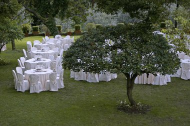 Düğün masaları ve sandalyeler düğün yemeği için bahçede hazır.