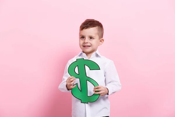 A happy kid holds a fake American green big dollar on a pink background. — Stock Photo, Image