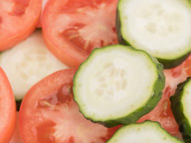Dilimlenmiş yeşil salatalık ve kırmızı domates en iyi görünümünü arka plan, closeup olarak. Salata için taze sebze kavramı