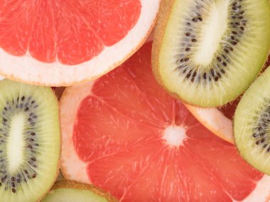 Kırmızı bir arka plan olarak dilimlenmiş greyfurt ve tohumları ile taze kivi. Narenciye vitamin dolu bir kavram