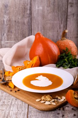 Kabak krem-çorba, bir tabak bileşimi bir balkabağı tohumları ahşap arka plan ile. Sonbaharda hasat ve Cadılar Bayramı kavramı.