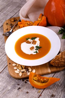 Kabak krem-çorba, bir tabak bileşimi bir balkabağı tohumları ahşap arka plan ile. Sonbaharda hasat ve Cadılar Bayramı kavramı.