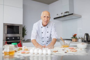 Yaşlı adam şef mutfakta hamur yoğurma. Çiğ hamur pizza yemeye hazırlanıyor unu yemek.