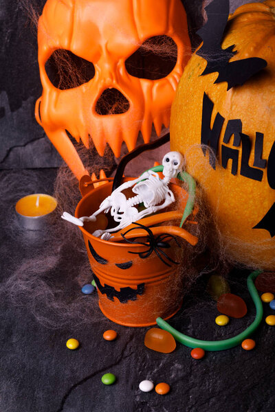 Тыква на Хэллоуин со свечами, пауками, паутиной, сладостями, ужастиками на тёмном фоне, крупным планом. Концепция осенних каникул
.