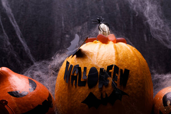 Тыква на Хэллоуин со свечами, пауками, паутиной, сладостями, ужастиками на тёмном фоне, крупным планом. Концепция осенних каникул
.