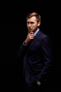 Siyah bir zemin üzerine sakallı genç bir düşünceli işadamı portresi. İş ve finans kavramı.