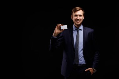 Takım elbiseli bir genç mutlu ve kendine güvenen işadamı portresi ile siyah bir zemin üzerine beyaz kağıdın yakın çekim. İş kavramı