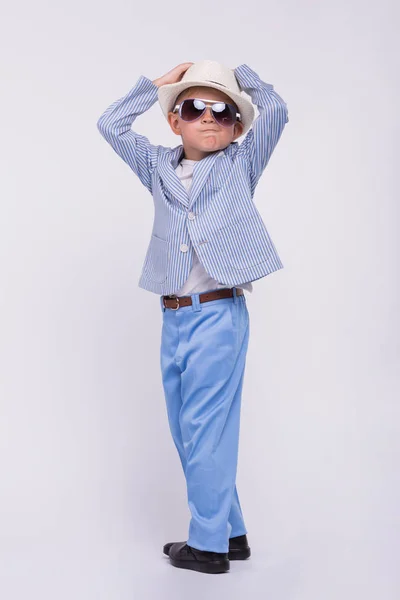 Un petit garçon heureux dans une lunette de soleil, un chapeau et dans un costume de mode isolé sur un fond blanc. Concept enfants drôles — Photo