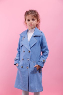 Bir mavi kot ceket pembe bir arka plan üzerinde küçük bir kız portresi. Sonbahar moda kavramı.