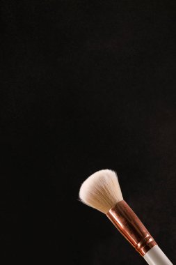 Siyah arka plan üzerine toz allık patlama ile kozmetik fırçalar makyaj. Cilt Bakımı ya da moda kavramı.