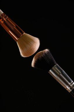 Siyah arka plan üzerine toz allık patlama ile kozmetik fırçalar makyaj. Cilt Bakımı ya da moda kavramı.