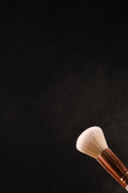 Siyah arka plan üzerine toz allık patlama ile kozmetik fırçalar makyaj. Cilt Bakımı ya da moda kavramı.