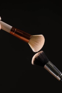 Siyah arka plan üzerine toz allık patlama ile kozmetik fırçalar makyaj. Cilt Bakımı ya da moda kavramı.