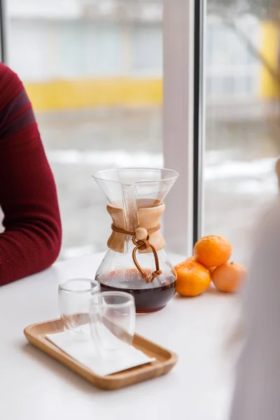 Una taza de té, un platillo, una rama de una planta viva, una mandarina anaranjada.Ambiente invernal con velas — Foto de Stock