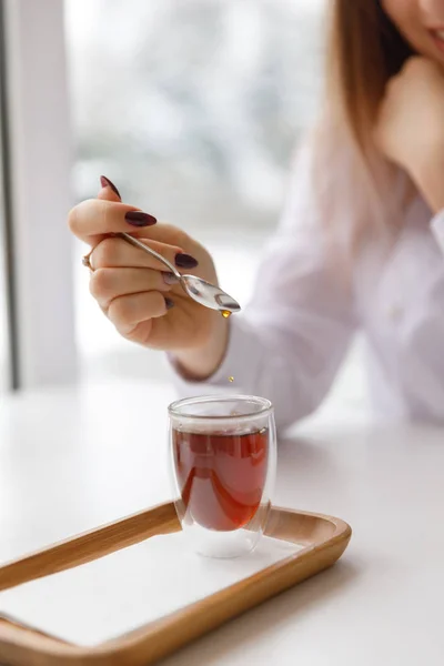 Una taza de té, un platillo, una rama de una planta viva, una mandarina anaranjada.Ambiente invernal con velas — Foto de Stock