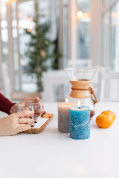 Чашка чая, блюдце, ветвь живого растения, апельсиновый мандарин. Зимняя атмосфера со свечами
