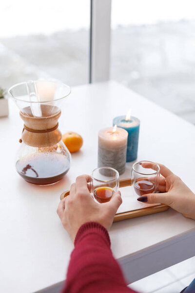 Чашка чая, блюдце, ветвь живого растения, апельсиновый мандарин. Зимняя атмосфера со свечами
