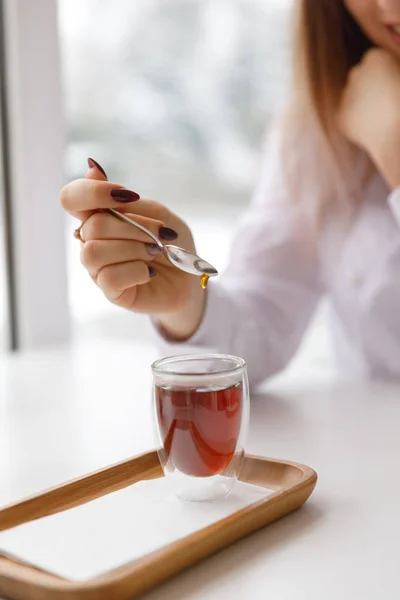 Una taza de té, un platillo, una rama de una planta viva, una mandarina anaranjada.Ambiente invernal con velas — Foto de Stock