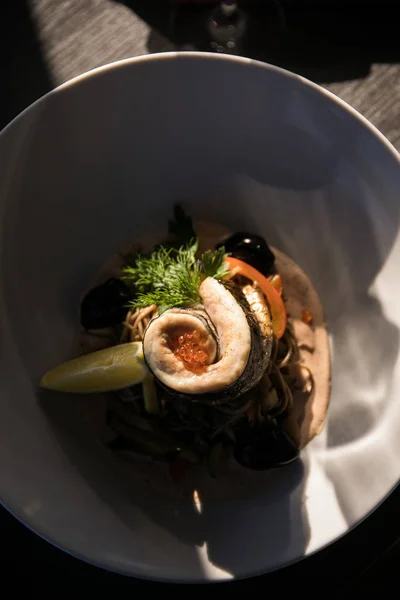 Pyszne ryby bułka z garnish warzyw i oliwki przyprawiona papryki na białym talerzu — Zdjęcie stockowe
