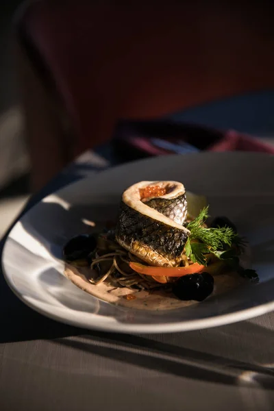 Pyszne ryby bułka z garnish warzyw i oliwki przyprawiona papryki na białym talerzu — Zdjęcie stockowe