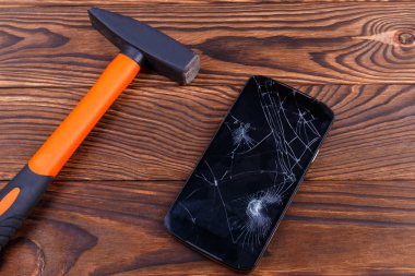 Dokunmatik ekran smartphone bir çekiç ile bir aygıt hatası kavramını bozuldu. Bir kırık dokunmatik ekran ve bir ahşap arka plan, bir çekiç ile smartphone aygıt kırmak