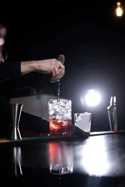 Expert barman is making cocktail at night club.bartender with cocktail and orange peel preparing cocktail at bar. alcohol drinks, people and luxury concept