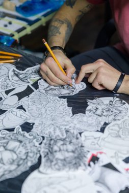 Yakın çekim fotoğraf profesyonel tattooer sanatçı dövme makinesi siyah mürekkeple kazanıyor ve gidiş adam yandan resim yapar. Sanat vücut üzerinde. Işık tattoo studio dövmeli yapmak için donatım -