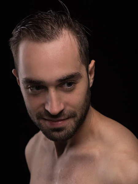 Concept studio portrait of a handsome young man isolated on a black background with different emotions in a blue shirt. He stands directly in front of the camera in various poses.