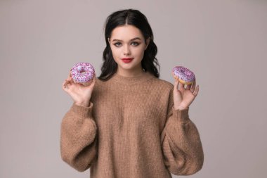 Kırmızı dudaklar çörek ve elma ile poz güzel kızla. Kameraya bakarak çok seksi esmer kız uzun saçlı, parlak kırmızı dudaklar, holding lezzetli çörek el ile.