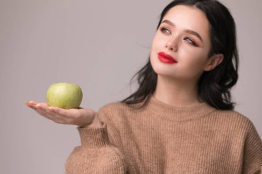 Çörek ve beyaz arka plan üzerinde izole yeşil elma arasında seçme karışık bir genç kadın portresi