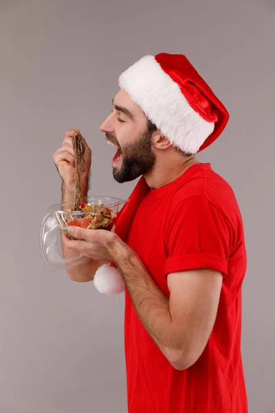 Bonito homem de chapéu de Natal segurando caixa com comida . — Fotografia de Stock