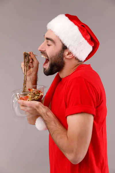 Beau homme dans un chapeau de Noël tenant boîte avec de la nourriture . — Photo