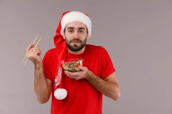 Красивый мужчина в рождественской шляпе держит коробку с едой . — стоковое фото