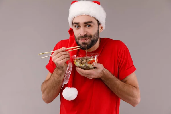 Красивый мужчина в рождественской шляпе держит коробку с едой . — стоковое фото
