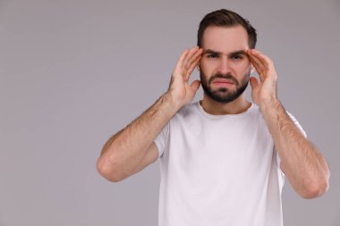 Gri bir arka plan üzerinde beyaz bir T-shirt bir sakallı şaşkın adam