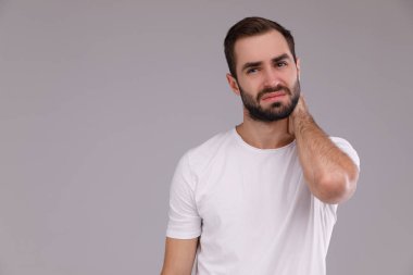 Gri bir arka plan üzerinde beyaz bir T-shirt bir sakallı şaşkın adam