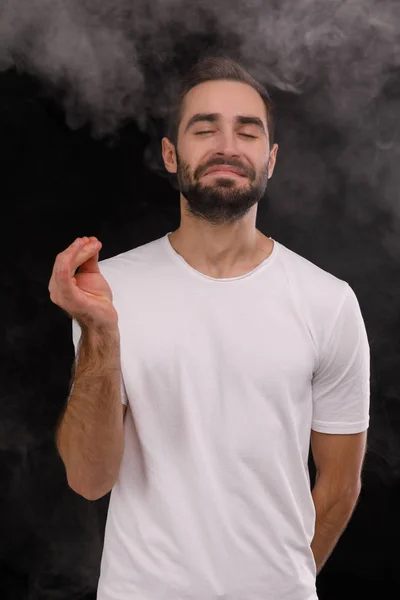 Парень в белой футболке вдыхает дым — стоковое фото
