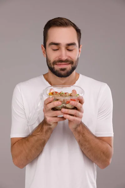 Un hombre come un tazón vegano con palillos. Un hombre sostiene poke bowl en sus manos —  Fotos de Stock